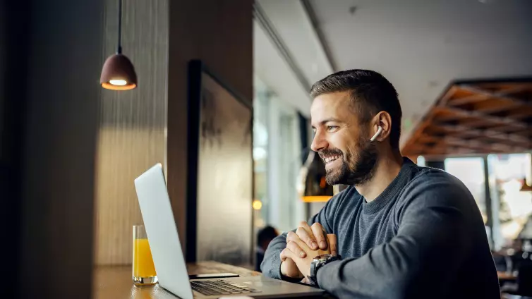 Man smiling using a laptop.