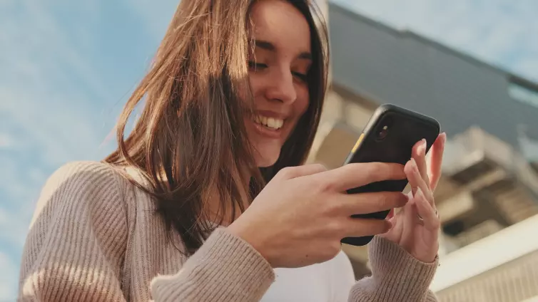 Close-up of a young woman using a mobile phone. Portrait of a happy girl typing a social media message on her mobile phone.