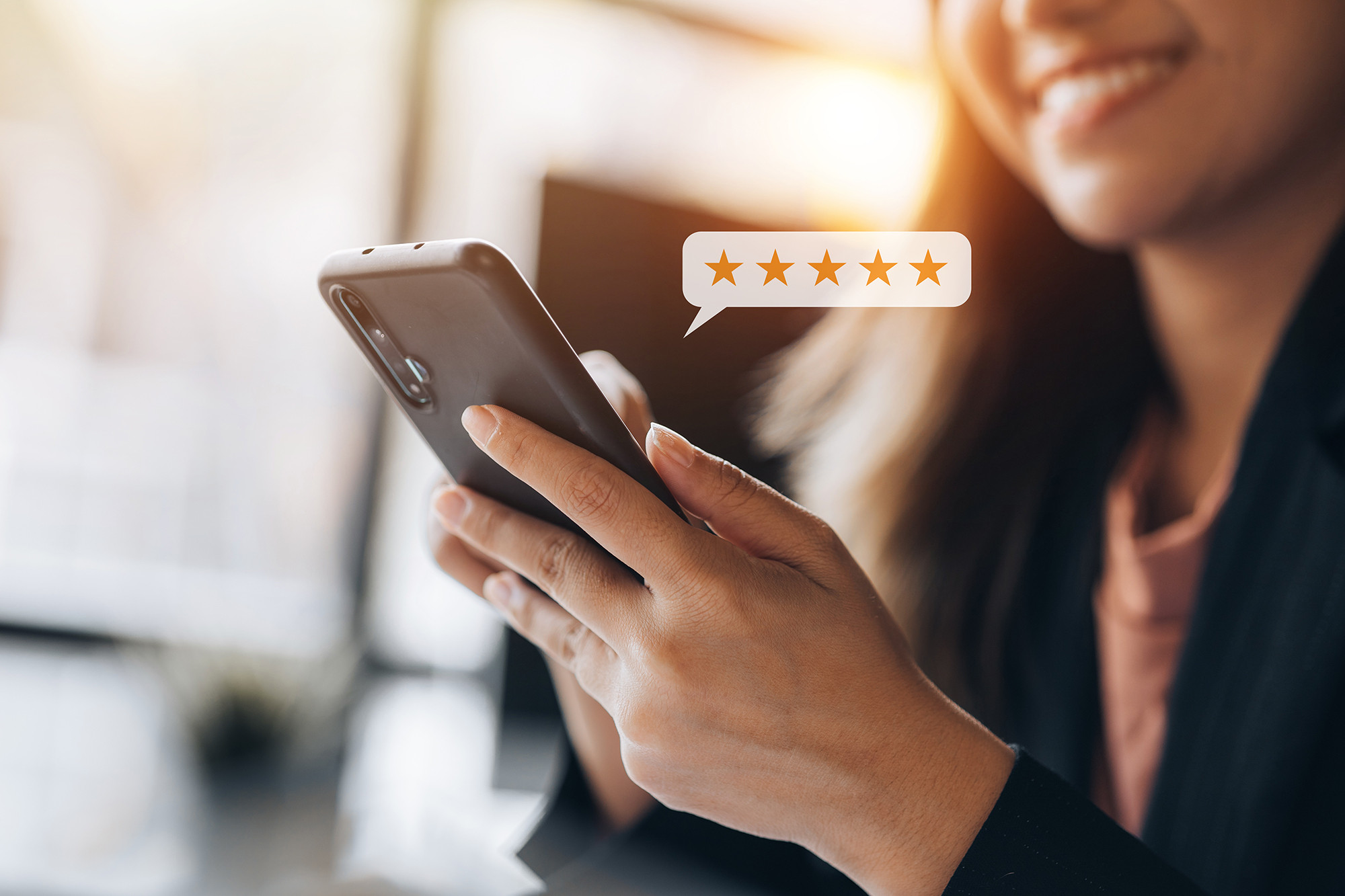 Smiling woman holding a smartphone with a five star rating graphic superimposed on the image.